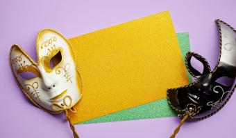 Two Venetian carnival masks are white and black on a lilac background.