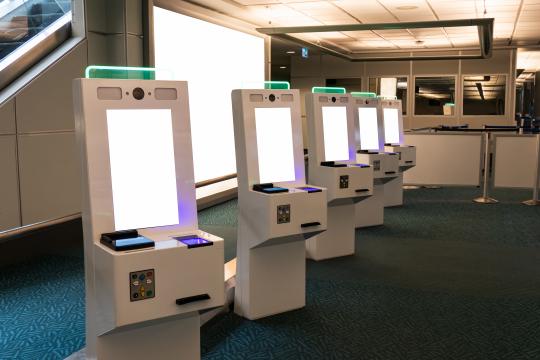 Self-service immigration terminals with IRIS, fingerprint scanner and passport scanner within the customs area of an airport.