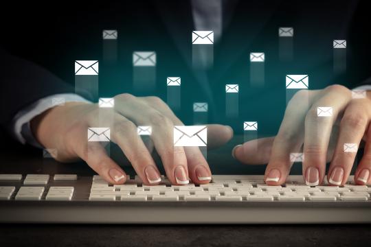 Woman is typing on a keyboard and many vector mail icons are flying across the image showing that Engity's customers can choose which user gets which customized mailing.