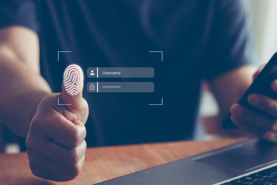 Der Einsatz der Multi-Faktor Authentifizierung (MFA) im Unternehmensumfeld wird gezeigt durch die Eingabe des Passwortes und Fingerabdruckes auf einem virtuellen Screen vor einem Notebook.