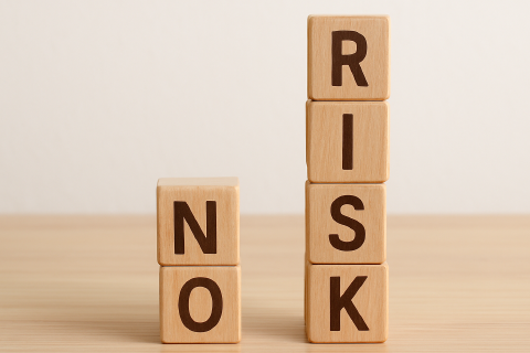 No risk when applying for funding Letters are written on wooden cubes stacked in two towers on a table, forming the words NO RISK.